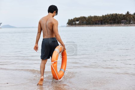 Photo for Lifeguard on Duty: A Joyful Asian Man Guarding the Beach, Saving Lives, and Ensuring Safety in the Sparkling Blue Ocean - Royalty Free Image