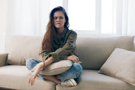 Téléchargez les photos : Femme seule sur le canapé, triste et inquiète : portrait de la crise de santé mentale à la maison - en image libre de droit