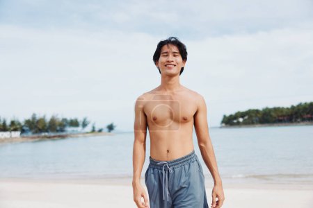 Téléchargez les photos : Athlète asiatique musclé profitant d'une course au coucher du soleil sur la plage - en image libre de droit