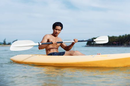 Photo for Adventure and Serenity: Asian Man Enjoying Kayaking on Tropical Beach - Royalty Free Image