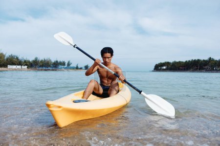 Photo for Summer Fun: Asian Man Kayaking on Tropical Beach with Palm Trees - Royalty Free Image