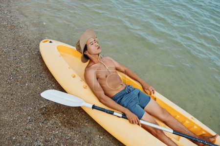 Photo for Happy Asian Man Kayaking on Tropical Beach, Enjoying Summer Vacation with Oar and Hat - Royalty Free Image
