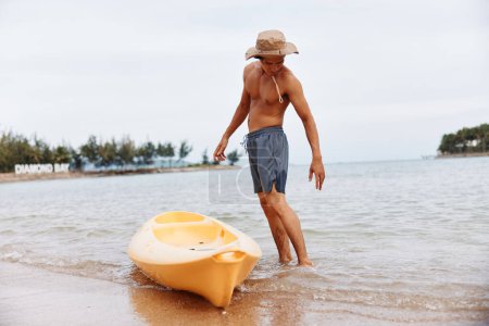 Téléchargez les photos : Heureux asiatique homme appréciant kayak aventure sur un tropical plage - en image libre de droit