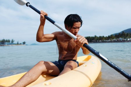 Foto de Hombre disfrutando de la aventura en kayak en la playa tropical: Recreación de agua activa y ocio - Imagen libre de derechos