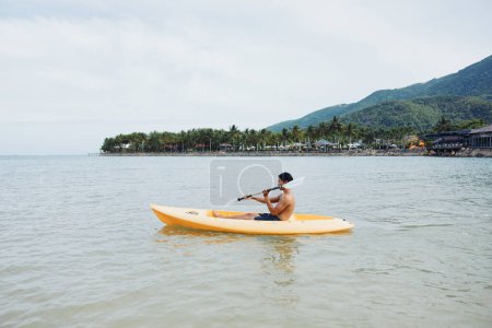 Téléchargez les photos : Actif asiatique l'homme avoir amusant kayak sur tropical plage - en image libre de droit