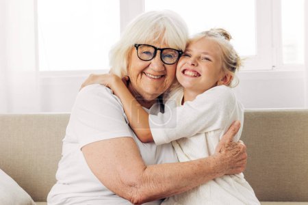 Photo for Mother woman child granddaughter bonding hugging happy old sofa hug home love grandmother lifestyle couch girl elderly family - Royalty Free Image
