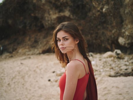Téléchargez les photos : Portrait d'une femme sur la plage en maillot de bain rouge avec les cheveux volants regardant la caméra. Photo de haute qualité - en image libre de droit