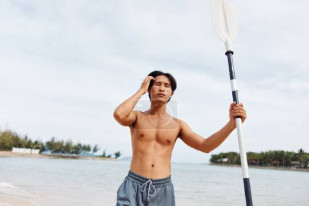 Téléchargez les photos : Actif asiatique l'homme appréciant pagayer aventure sur l 'plage - en image libre de droit