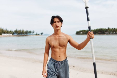 Téléchargez les photos : Homme asiatique actif pagayer sur une plage au coucher du soleil, profiter des sports nautiques aventure - en image libre de droit