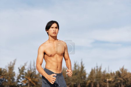 Téléchargez les photos : Musclé asiatique homme profiter de plaisir et de détente à une plage tropicale - en image libre de droit