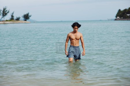 Téléchargez les photos : Swimming Man in Tropical Paradise : Des vacances asiatiques joyeuses au bord de l'océan bleu - en image libre de droit