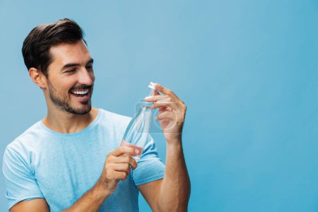 Téléchargez les photos : Homme sourire t-shirt frais sport bleu gai bouteille saine portrait heureux fond boire studio style de vie isolé attrayant main eau boisson - en image libre de droit