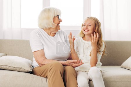 Photo for Woman lifestyle generation child old love joy happy daughter hug girl grandmother sofa grandchild indoor granddaughter couch sitting family home senior mother elderly - Royalty Free Image