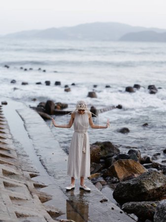 Téléchargez les photos : Beauté en été : Une jeune femme jouissant d'une promenade romantique pieds nus sur la plage de sable blanc avec une vue imprenable sur l'océan - en image libre de droit