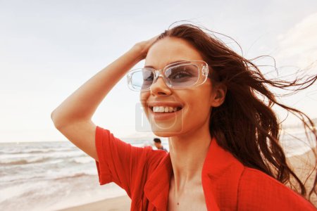 Téléchargez les photos : Femme souriante au coucher du soleil coloré : Portrait d'un vacancier joyeux embrassant la liberté sur une plage branchée - en image libre de droit