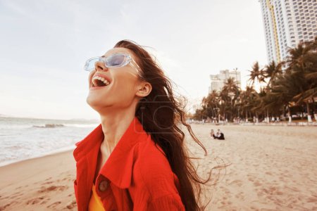 Foto de Sunny Bliss: Un retrato colorido de una mujer sonriente disfrutando de libertad y felicidad en la playa - Imagen libre de derechos