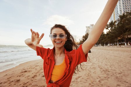 Téléchargez les photos : Femme souriante : Faire place à la liberté sur la plage colorée au coucher du soleil - en image libre de droit