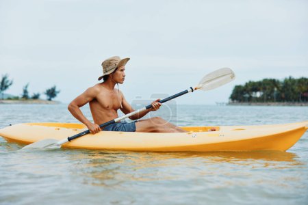 Téléchargez les photos : Happy Asian Man kayak sur une plage tropicale, profiter des vacances d'été - en image libre de droit