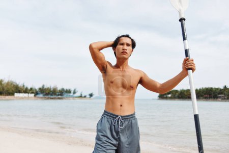 Foto de Hombre remando al atardecer: Viajero asiático abrazando la diversión y la aventura de los deportes acuáticos en unas vacaciones en la playa - Imagen libre de derechos