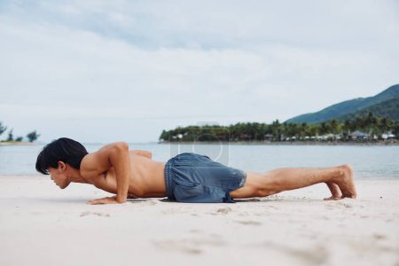 Téléchargez les photos : Athlète asiatique actif profitant de la plage en cours d'exécution au coucher du soleil d'été - en image libre de droit