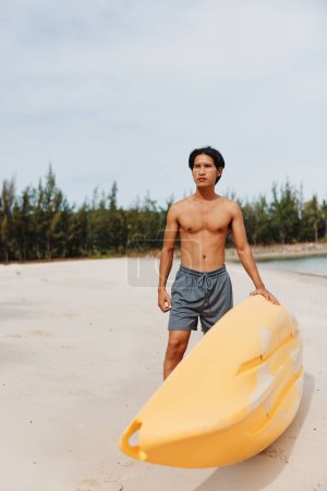 Téléchargez les photos : Escapade estivale amusante : Homme asiatique faisant du kayak sur une plage tropicale, profitant d'une aventure de sport nautique - en image libre de droit
