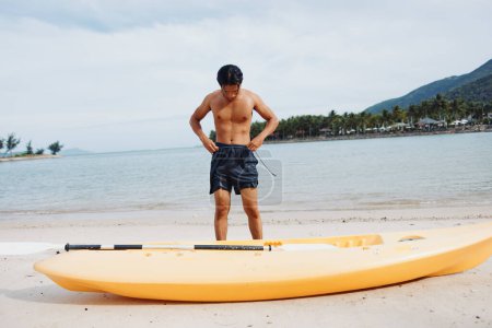 Téléchargez les photos : Plaisirs d'été : Happy Young Asian Man Kayak sur Tropical Beach - en image libre de droit