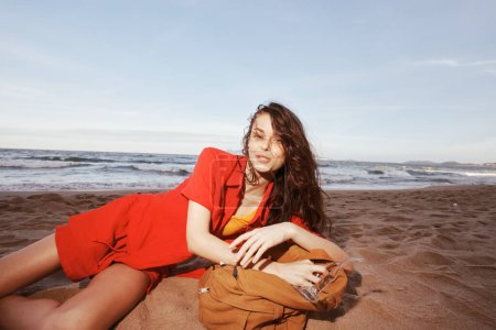 Téléchargez les photos : Joyful Traveler : Une femme sac à dos Vivre l'aventure relaxante d'un séjour à la plage - en image libre de droit