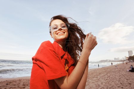 Téléchargez les photos : Femme souriante et insouciante profitant d'un coucher de soleil coloré à la plage, embrassant la liberté et le bonheur - en image libre de droit