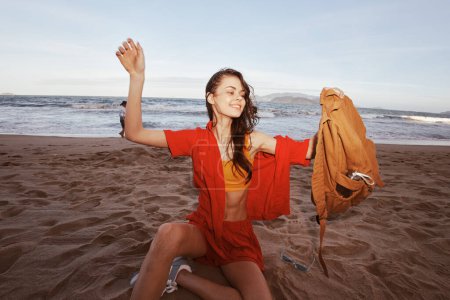 Téléchargez les photos : Délice des voyageurs : Joyeuse femme Randonnée pédestre à travers Natures Paradise, Détente sur une plage de sable fin au bord de la mer - en image libre de droit