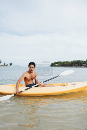 Téléchargez les photos : Sérénité et aventure : "Un Asiatique qui s'amuse en kayak sur une plage tropicale" - en image libre de droit