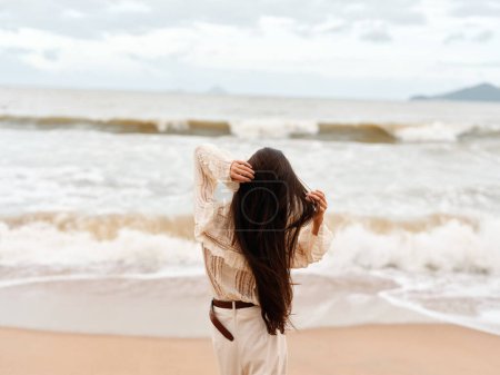 Téléchargez les photos : Solitude sereine : Une jeune femme se promène tranquillement le long du bord majestueux des océans - en image libre de droit