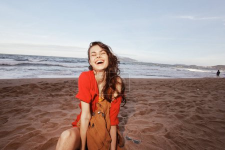 Téléchargez les photos : Voyageurs Bliss : Un joyeux randonneur embrassant les natures Sérénité sur une plage au bord de la mer - en image libre de droit