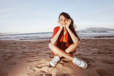 Photo for Carefree Woman Sitting on a Sunny Beach, Smiling and Enjoying a Relaxing Vacation - Royalty Free Image