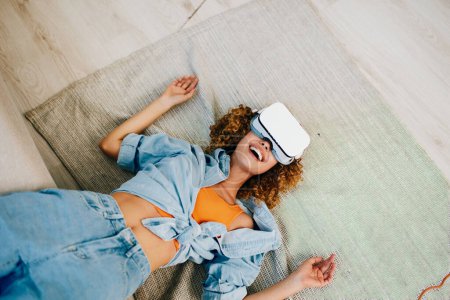 Foto de Mujer sonriente usando gafas de realidad virtual en casa, disfrutando del juego cibernético futurista - Imagen libre de derechos