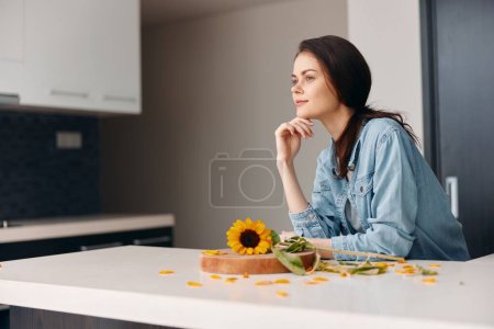 Foto de Triste y sensual: un retrato de una joven infeliz cocinando ensalada vegetariana saludable en una cocina bastante blanca - Imagen libre de derechos