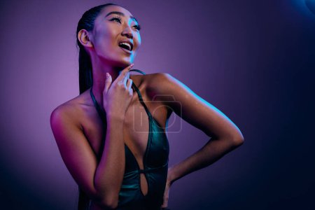 Téléchargez les photos : Femme slim bleu glamour asiatique brillant lumière néon disco jusqu'à briller violet jolie luxe dame sombre tendance beauté coloré peau mode brillant noir faire - en image libre de droit