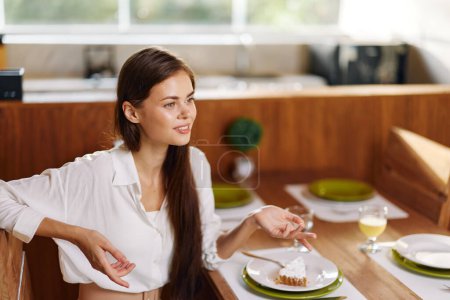 Foto de Mujer feliz disfrutando de una cena romántica con un pastel casero y vino en un comedor de moda - Imagen libre de derechos