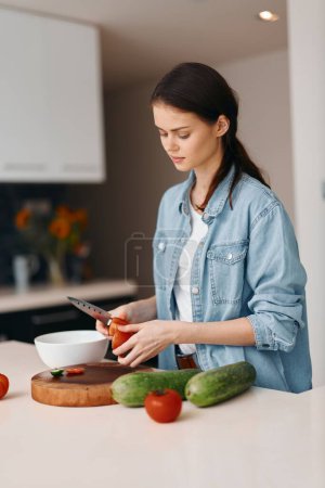 Téléchargez les photos : Cuisiner un mode de vie sain : Jeune femme dans une belle cuisine, Préparation de légumes frais pour une salade végétalienne. - en image libre de droit
