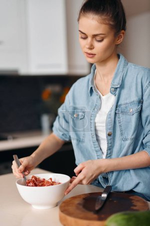 Téléchargez les photos : Cuisine Beauté : Une jeune cuisinière prépare une salade végétarienne saine à la maison - en image libre de droit
