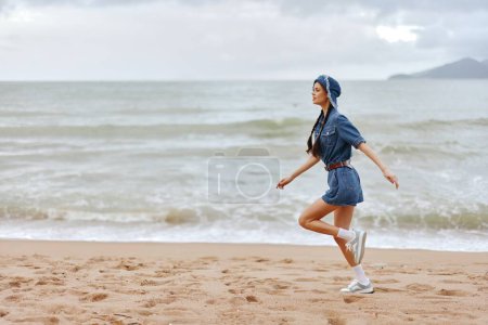 Photo for Healthy Beach Lifestyle: Young Woman Running on Sand by the Ocean, Exuding Beauty and Energy in Sportswear - Royalty Free Image