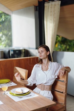 Foto de Mujer feliz disfrutando de una deliciosa cena casera en la mesa de comedor de moda con pastel romántico y vino - Imagen libre de derechos