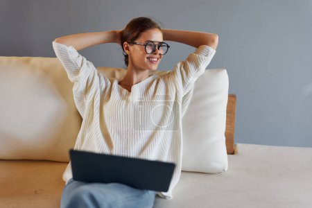 Téléchargez les photos : Happy Woman travaillant sur ordinateur portable dans le bureau à domicile confortable sur un matin paresseux - en image libre de droit