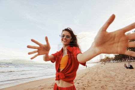 Photo for Smiling Woman in Colorful Sunglasses Embracing Freedom at Sunset Beach - Royalty Free Image