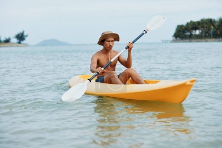 Téléchargez les photos : Asiatique homme profiter de kayak aventure sur Tropical plage avec palmiers et cristal clair océan eau - en image libre de droit