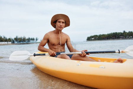 Photo for Happy Asian Man Kayaking in Tropical Paradise with Palm Trees and Turquoise Waters - Royalty Free Image
