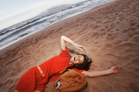 Téléchargez les photos : Voyageur joyeux : Une femme insouciante sac à dos sur une plage ensoleillée, profiter de la beauté ivre des natures - en image libre de droit