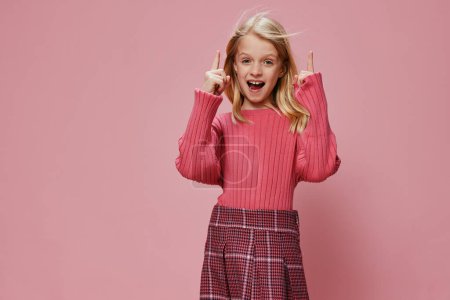 Téléchargez les photos : Écolière heureuse avec des accessoires roses élégants Souriant en studio, exprimant joie et excitation - en image libre de droit