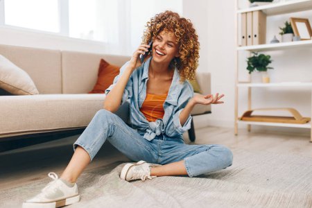 Photo for Connected Bliss: A Smiling Woman Holding a Mobile Phone, Relaxing on the Sofa in a Cozy Home - Royalty Free Image