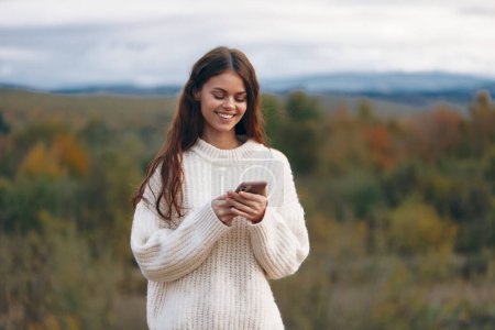 Téléchargez les photos : Femme de montagne Parler au téléphone, profiter de la liberté et de la nature : un voyageur d'aventure souriant Prendre un selfie dans le cyberespace - en image libre de droit
