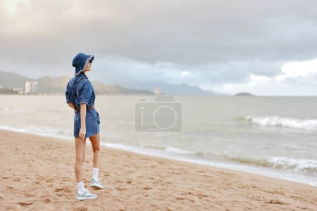 Téléchargez les photos : Sunny Beach : Une jeune femme se relaxant promenade sur le sable, profiter de la liberté et la beauté de l'océan tropical. - en image libre de droit